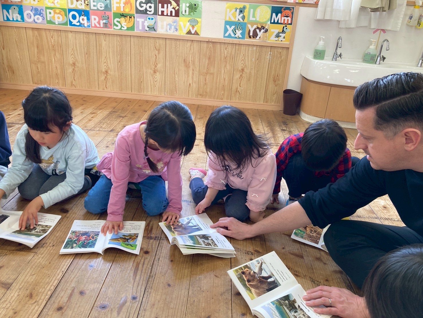 先生と園児が一緒に英語の本を読む様子